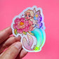Sticker of a fairy holding a flower against a pink background