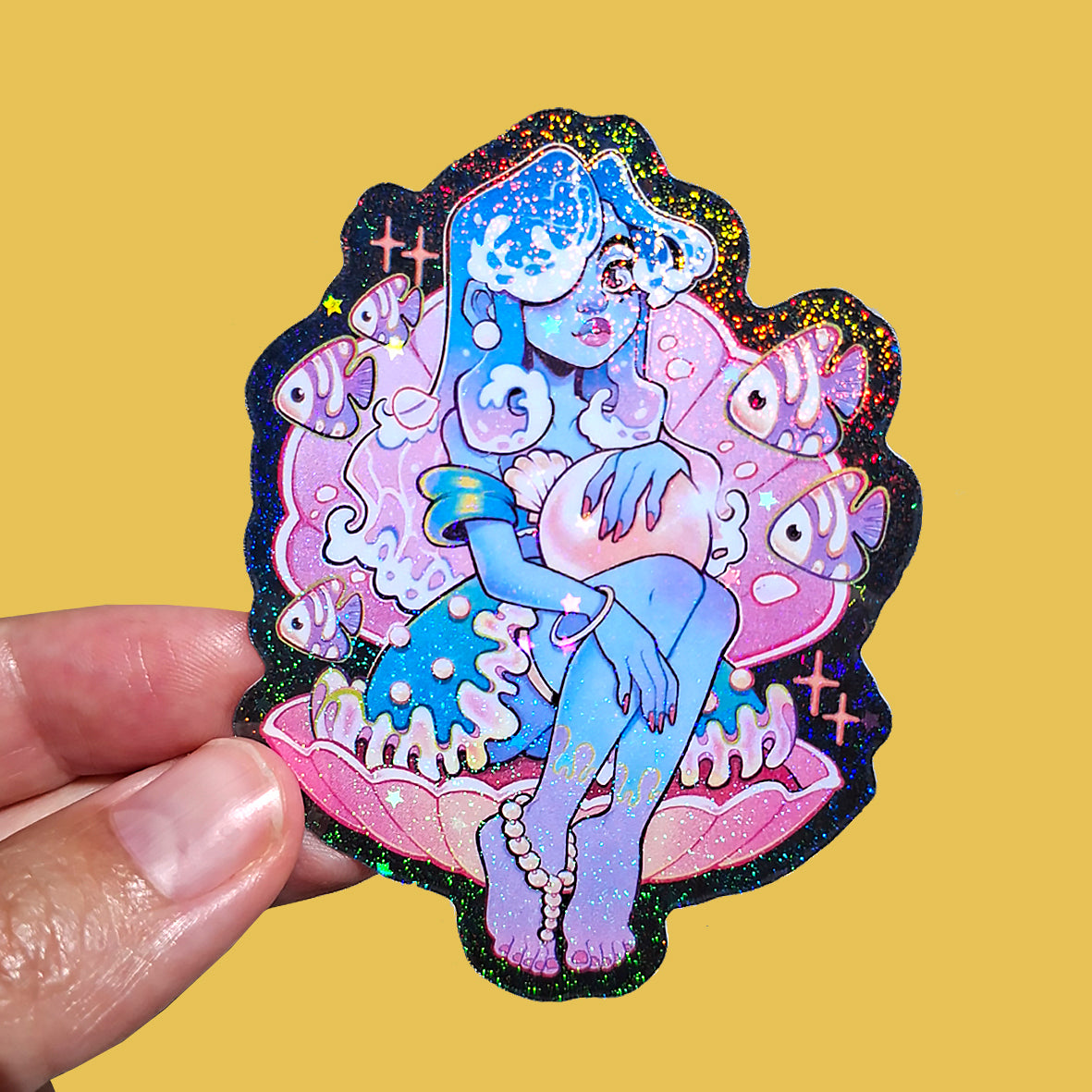 Colorful sticker of a fantasy character held by a hand on a yellow background